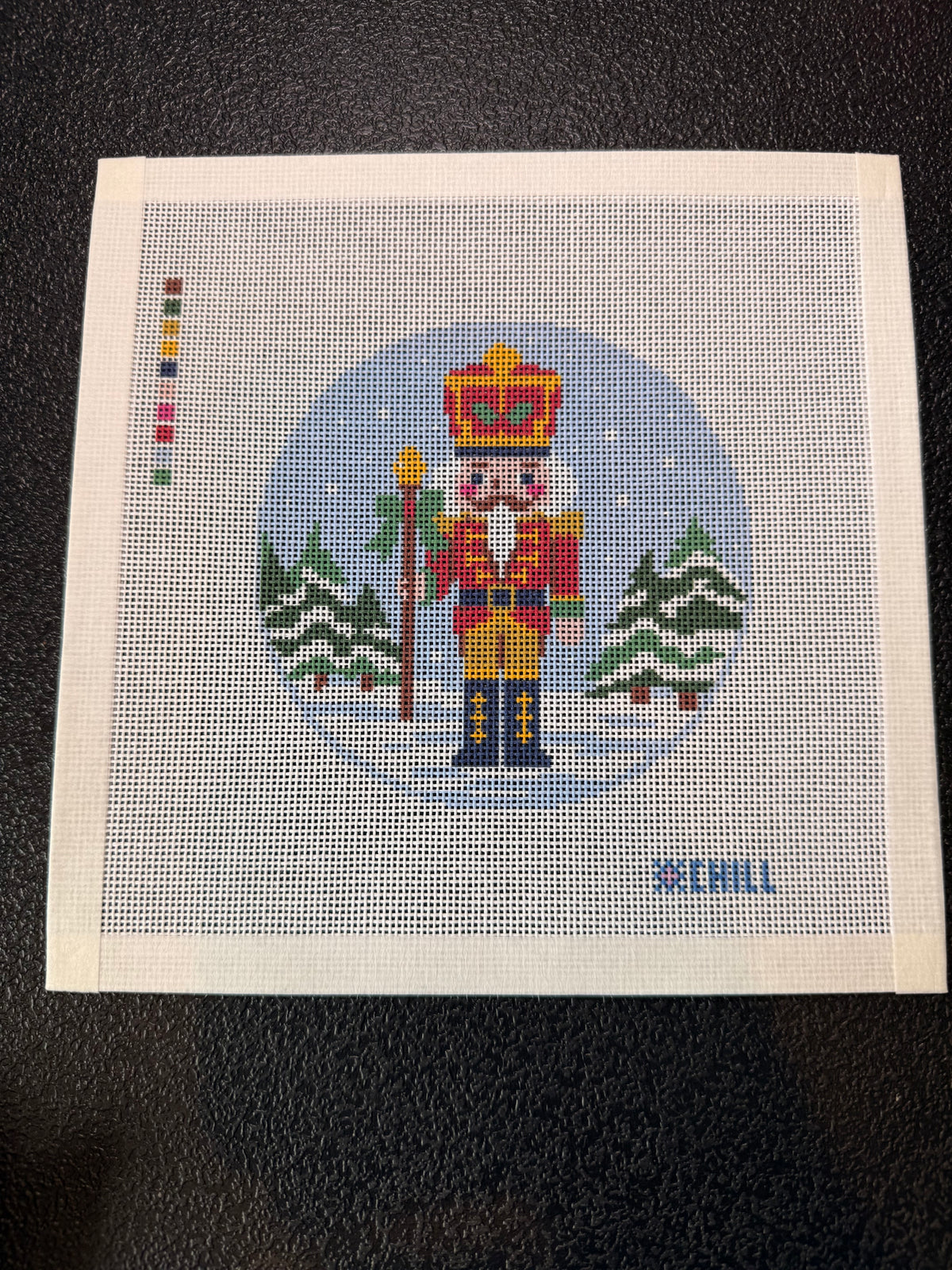 Detail of nutcracker crown, scepter and red coat on needlepoint canvas